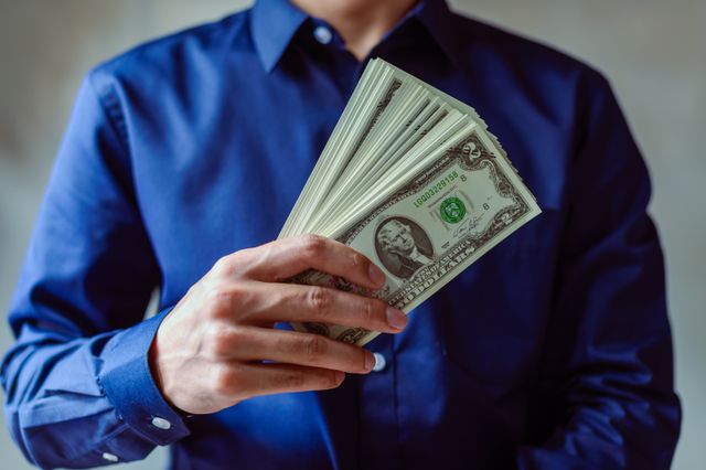 Close-up of a person in blue shirt holding money