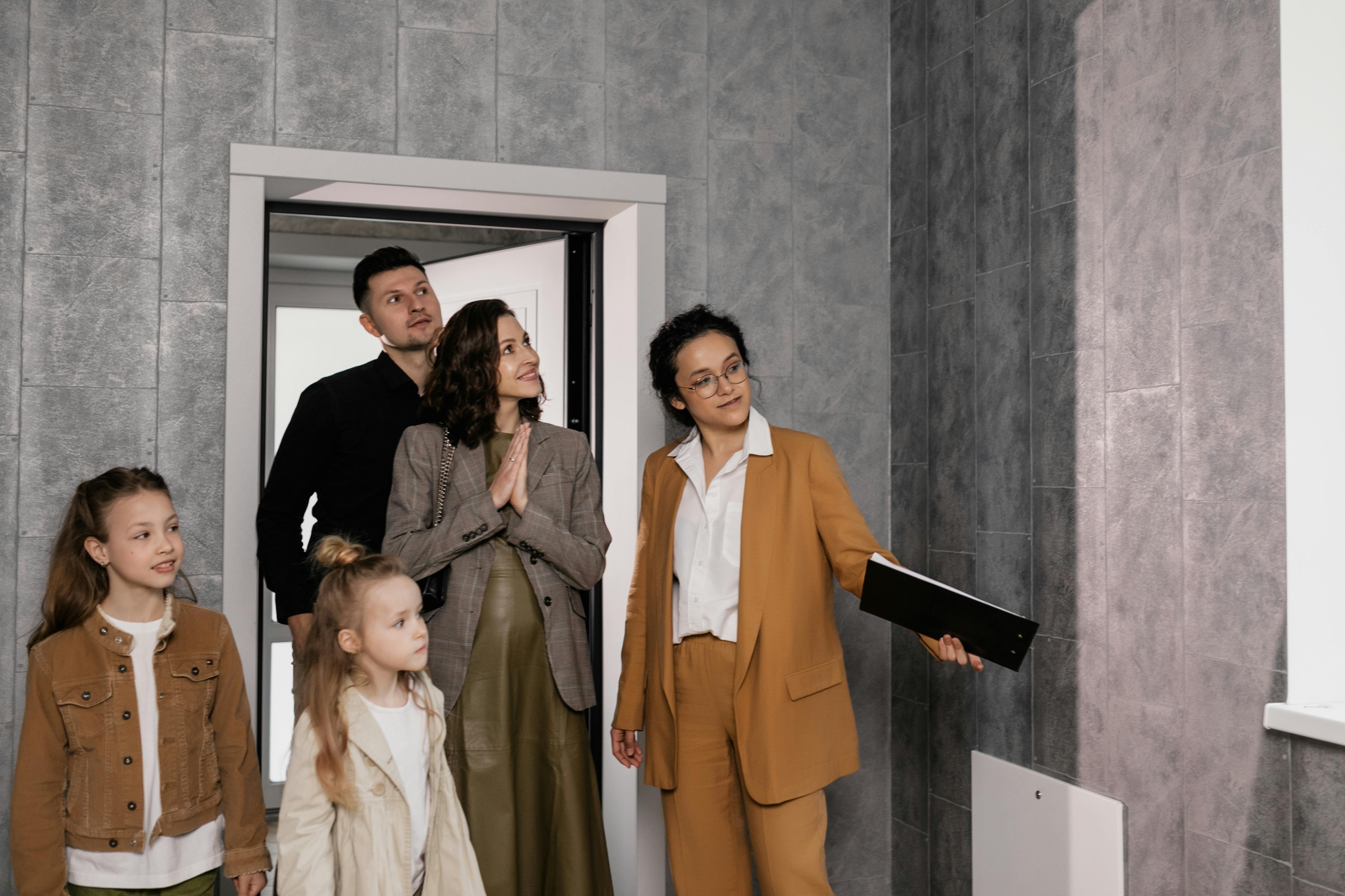 woman in tan suit and glasses showing a family of four through a house