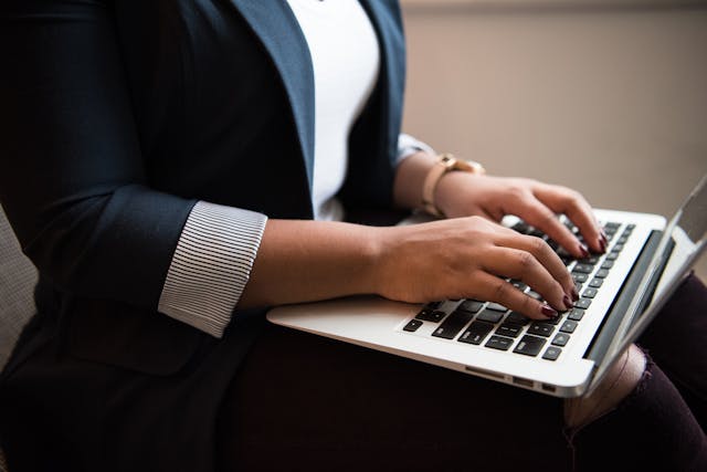 someone in a suit typing on a laptop