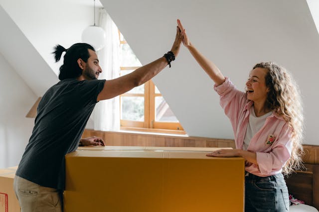 two people high-fiving over a large moving box