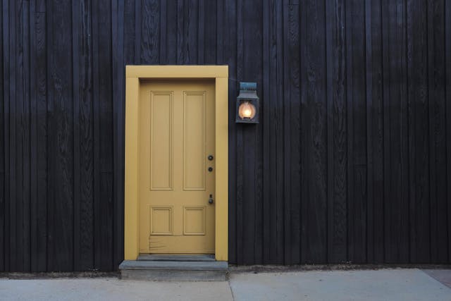 yellow door against dark wood with a lamp