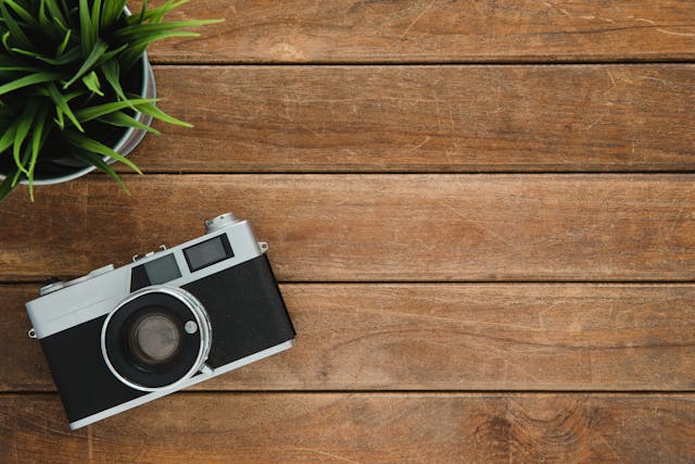 a camera on a wooden table next to a plant