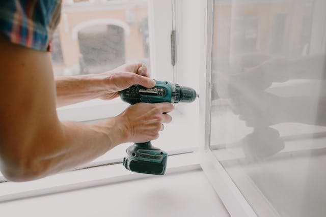 A person using a drill to install a window