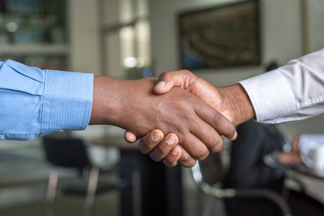 two people wearing long sleeves shirts shaking hands